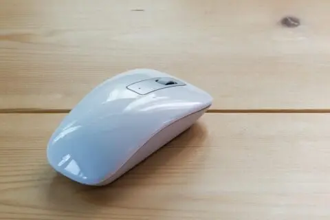 White wireless computer mouse on wooden desk