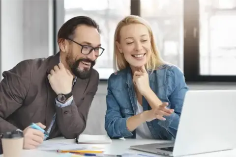 Two colleagues discussing work at a laptop.
