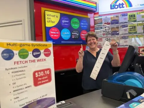 Woman holding lottery ticket inside Lott store